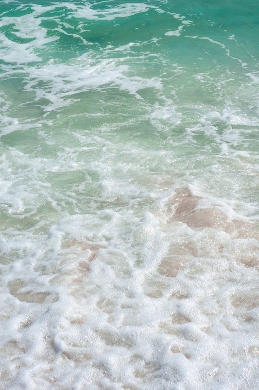 Fine art photography featuring teal waters swirled with salty ocean spray as the wave crashes against the shore.